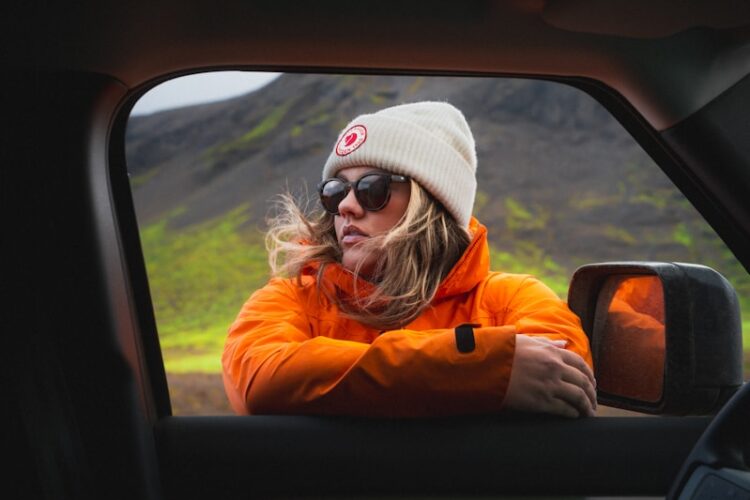 A woman in an orange jacket in a car